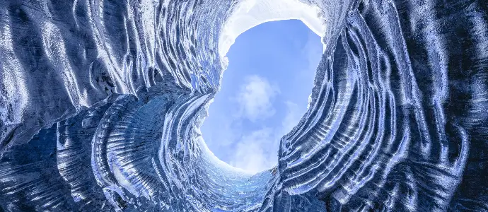 looking up from inside a snowy cave to a blue beautiful sky